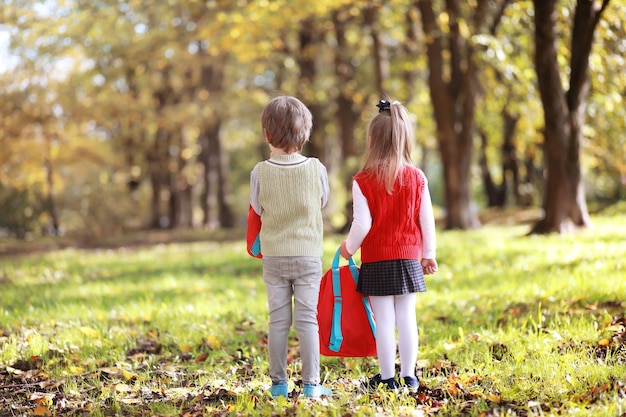 Kinderen met aktetassen voor een wandeling in het park. Schoolpauze. Het begin van de kinderstudies.