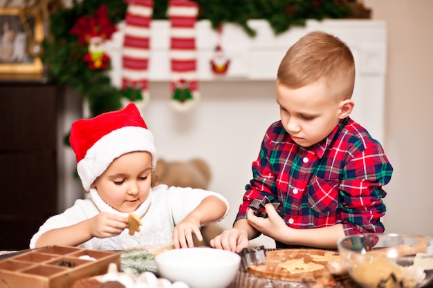 Kinderen met een kerstmuts thuis kerstkoekjes bakken