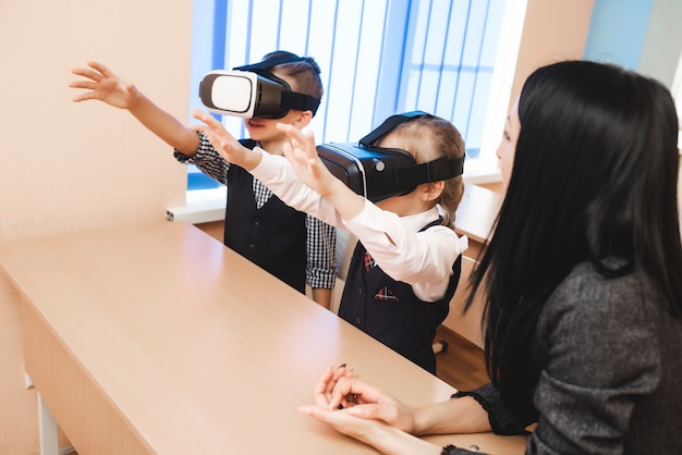 Kinderen met een virtual reality-bril zitten op school. Moderne lesmethoden