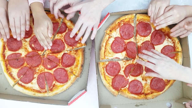 Foto kinderen met handen die pizza houden met salami top view