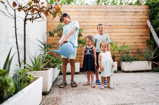 Kinderen met kan de bloemen water geven op het terras van het huis