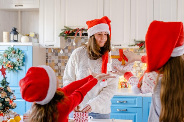 Kinderen met kerstmutsen geven een cadeau aan hun moeder