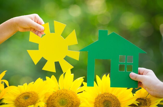 Kinderen met papieren huis en zon in handen buitenshuis