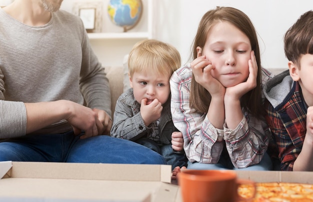 Kinderen met trek die thuis naar pizza kijken