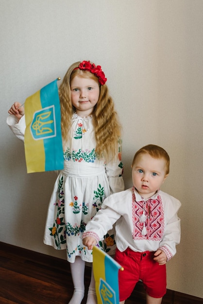 Kinderen met vlag Oekraïne gekleed in Oekraïense folk geborduurde kleding Nationale etnische traditionele klederdracht of jurk Een kind meisje met een krans van klaprozen op zijn hoofd Oekraïense douanetradities