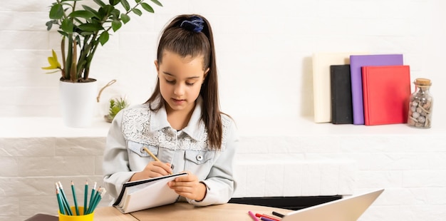 kinderen, onderwijs en leren op afstand concept - klein studentenmeisje met laptop thuis