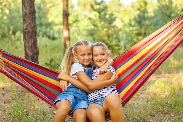 Kinderen ontspannen in kleurrijke regenbooghangmat Warme dag tuin buitenplezier Middagdutje tijdens zomervakantie Kinderen ontspannen