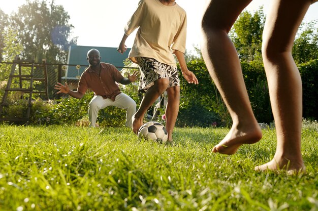 Kinderen op blote voeten en hun vader spelen samen voetbal op het groene gazon