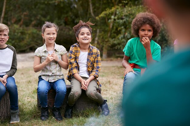 Kinderen op buitenactiviteit Camping Trip zitten samen rond het kampvuur