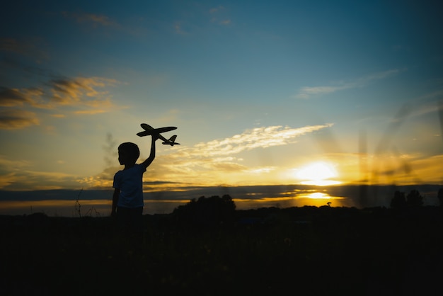 Kinderen op de achtergrond van de zon met een vliegtuig in de hand