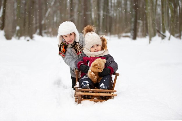 Kinderen op een houten slee op een winterdag Actieve buitenspellen voor kinderen in de winter