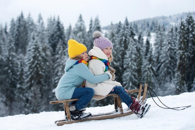 Kinderen op slee kinderen jongen en meisje spelen buiten in de sneeuw wintervakantie en kerst