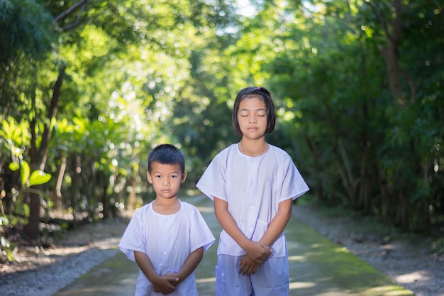 Kinderen op witte kleding, beoefen wandelen meditatie in bosboom met vrede in min