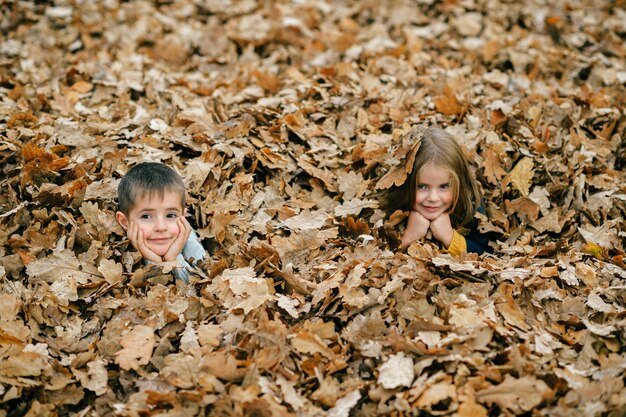 Kinderen poseren in de herfstbladeren