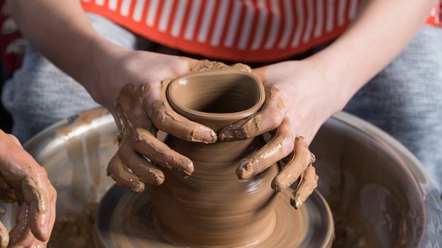 Kinderen pottenbakken leren. De docent geeft een masterclass in modelleren