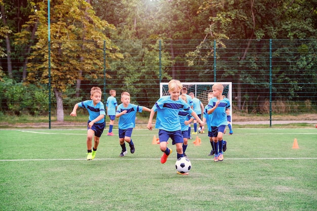 Kinderen rennen en schoppen voetballen op kindervoetbaltraining