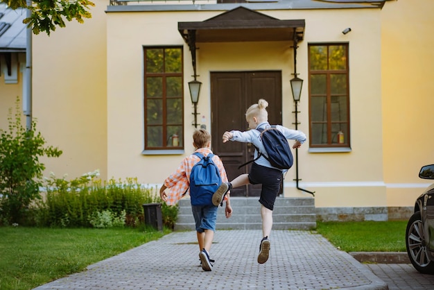 Kinderen rennen naar school met rugzakken op zonnige dag begin van academisch jaar jongens voor de deur van de school