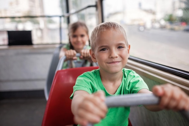 Kinderen rijden in een lege tram en kijken met een glimlach naar het raam met de stadstram van het openbaar vervoer