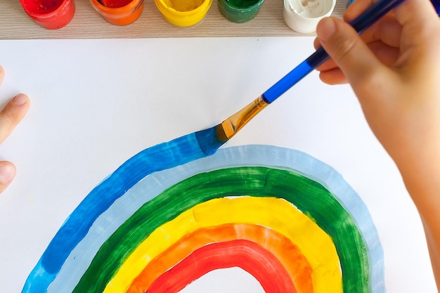 Kinderen schilderen aquarel regenbogen aan tafel thuis kunst en handwerk