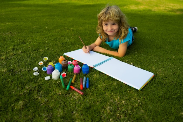 Kinderen schilderen met verf kleur en penseel in park buiten gelukkig kind spelen buiten tekenen zomer...