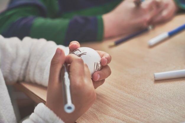 Kinderen schilderen paaseieren met de hulp van hun moeder en met markeringen thuis