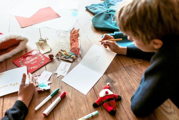 Kinderen schrijven kerstkaarten op houten vloer