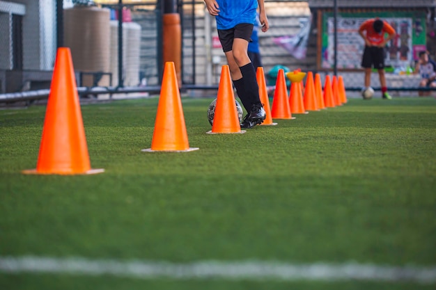 Kinderen spelen controle voetbal bal tactiek kegel op grasveld met voor opleiding achtergrond Kinderen trainen in voetbal