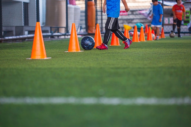 Kinderen spelen controle voetbal bal tactiek kegel op grasveld met voor opleiding achtergrond Kinderen trainen in voetbal