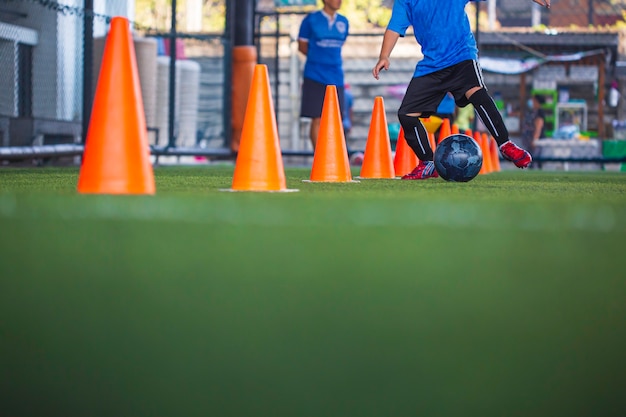 Kinderen spelen controle voetbal bal tactiek kegel op grasveld met voor opleiding achtergrond Kinderen trainen in voetbal