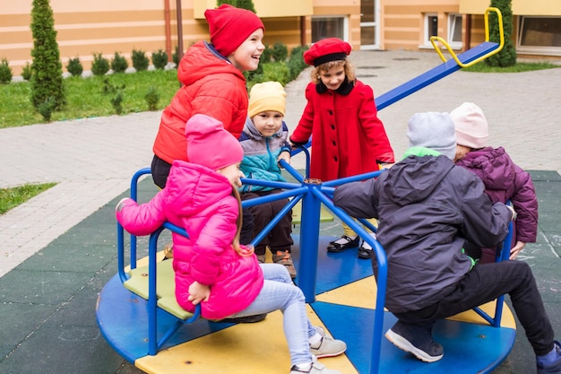 Kinderen spelen in de speeltuin buiten bij de lente Meisje zit op een carrousel Gelukkige tijd op de speelplaats Gelukkige jeugd