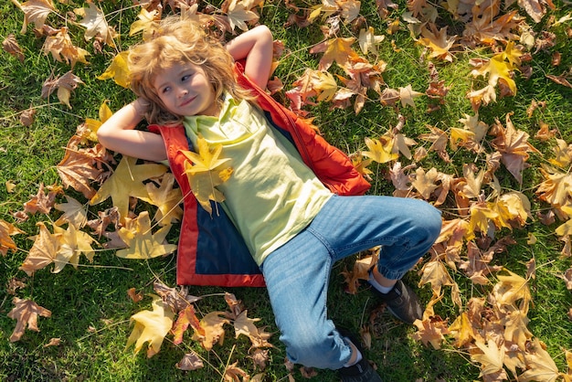 Kinderen spelen in het herfstpark Kinderportret met gele bladeren Kindjongen met eiken en esdoornblad buiten