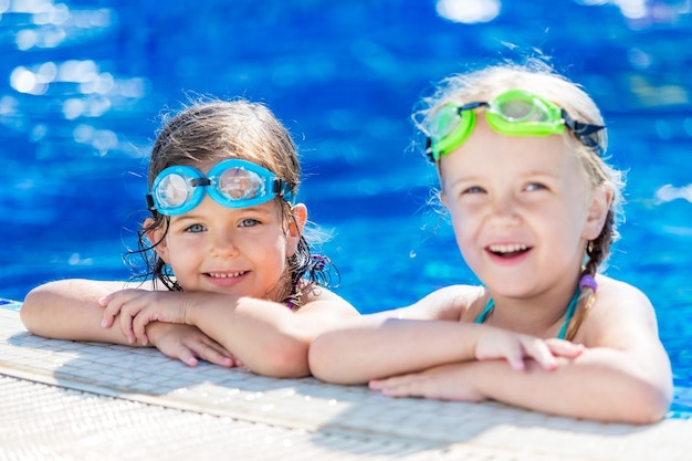 Foto kinderen spelen in het zwembad. twee kleine meisjes hebben plezier in het zwembad.