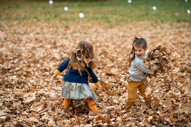 Kinderen spelen met herfstbladeren