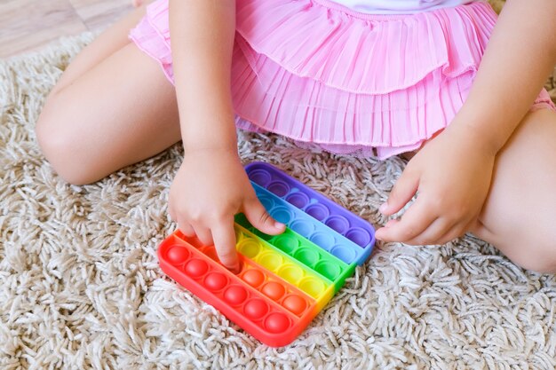 Kinderen spelen met pop it sensorisch speelgoed. Stress en angstverlichting. Trendy siliconen friemeltje voor gestresste kinderen en volwassenen. Squishy zacht bubbelspeelgoed.