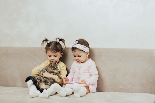 Kinderen spelen met schattige kat op de bank in de woonkamer