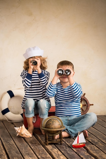 Kinderen spelen met vintage nautische dingen Kinderen hebben plezier thuis Reis- en avontuurconcept Retro getinte afbeelding