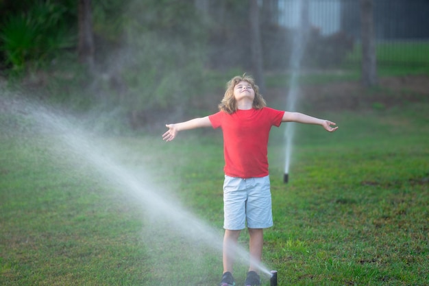 Kinderen spelen met water slang sprinkler water gras in de tuin zomer tuin buiten plezier voor kind