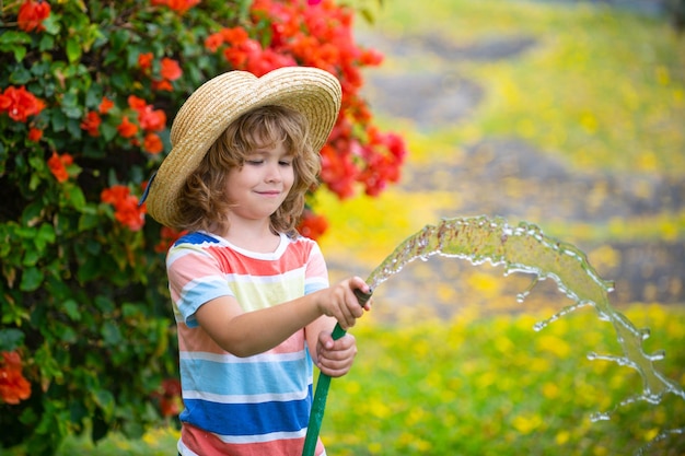 Kinderen spelen met water tuinslang in de tuin. Zomerplezier voor buiten kinderen. Kleine jongen spelen met waterslang in achtertuin. Feestspel voor kinderen. Gezonde activiteit voor warme zonnige dag.