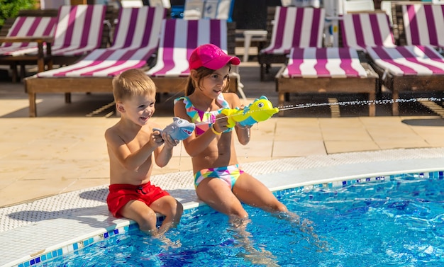 Kinderen spelen met waterpistolen in het zwembad. Selectieve aandacht. Water.