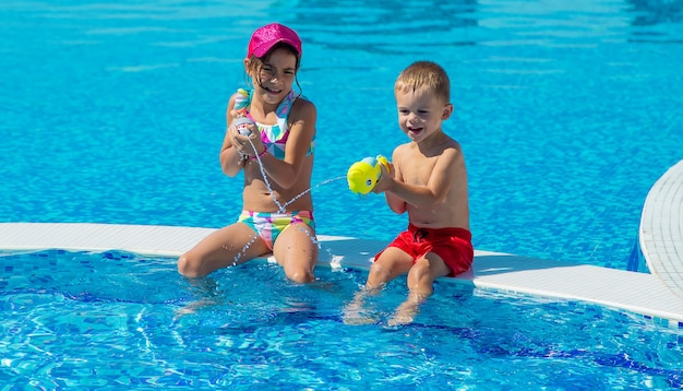 Kinderen spelen met waterpistolen in het zwembad. selectieve aandacht.