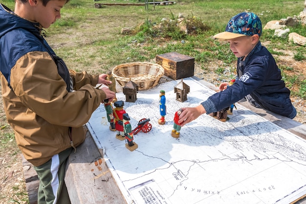 Kinderen spelen oorlog met houten figuren van soldaten op de oude kaart van Rusland