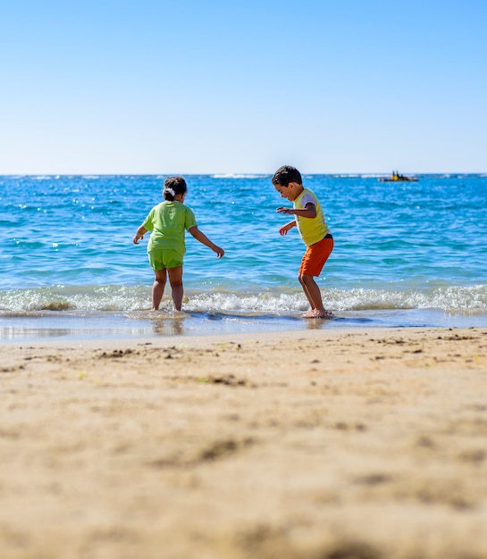 Kinderen spelen op zee kust onder zonlicht