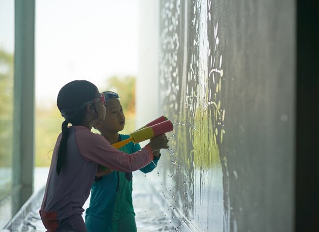 Kinderen spelen waterpistool tegen muur