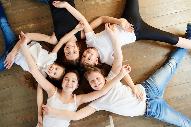 Kinderen staan in een kring. vijf meisjes op het bovenaanzicht van de houten vloer.