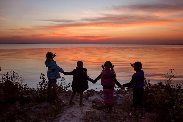 Kinderen staan samen hand in hand en kijken naar zonsondergang geweldige silhouetten actief familieweekend