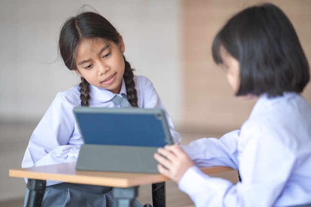 Kinderen student terug naar school studeren samen met behulp van digitale tablet en schrijven op notebook op school