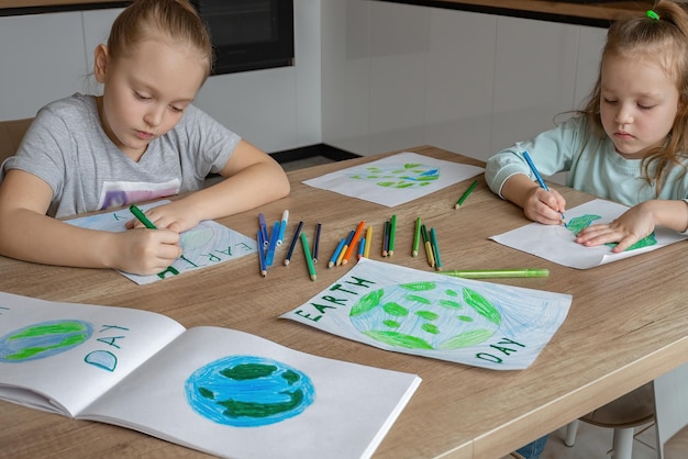 Kinderen tekenen de planeet aarde met potloden en viltstiften op albumbladen voor earth day