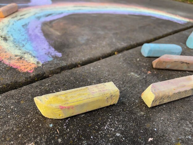 Kinderen tekenen regenboog met gekleurde krijt op het asfalt op een zonnige zomerdag