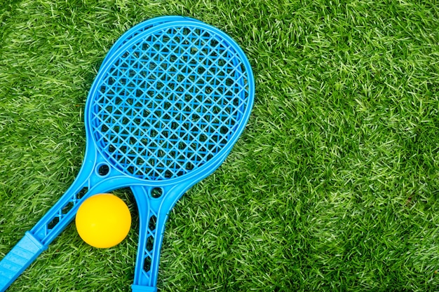 Kinderen tennisrackets en een bal op een groen gazon, zomer buitensportactiviteiten.