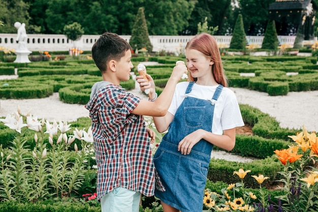 Kinderen tieners jongen en meisje hebben plezier op een zomerdag tegen de achtergrond van groen, ijs eten